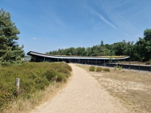 
                            <b>Modern gebouw met gebogen dak en glazen voorkant, omgeven door natuur.</b><br>
                                                        <b>ISO:</b> 50 | <b>Sluitertijd:</b> 1/1543 | <b>Diafragma:</b> f/1.8 | <b>Datum:</b> 2025-06-25

                        