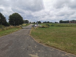 Afgesloten landweg met hek en geparkeerde auto’s