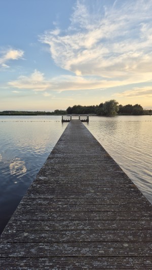 Een lange steiger over het Oldambtmeer met de Kikkerberg aan de overkant