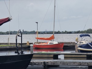 Rode zeilboot aangemeerd aan een steiger bij het Schildmeer.